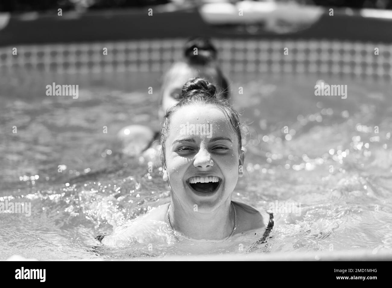 Happy children swim in swimming pool on sunny summer day, summertime