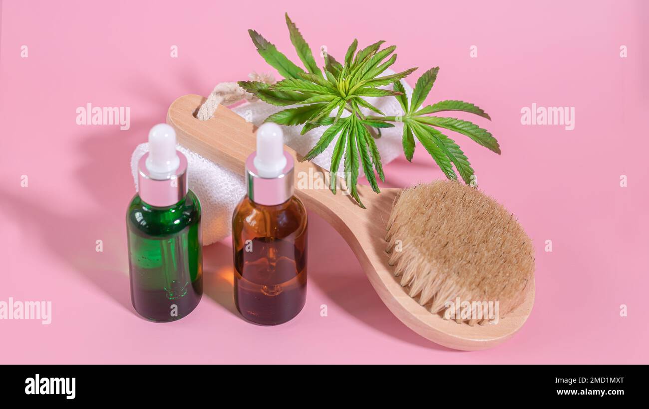 Black and green glass non-branded cosmetic oil and cannabis essential oil bottles and natural bristle wooden facial cleansing brush. Natural skin care Stock Photo