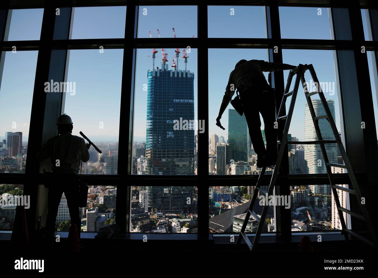 Workers clean the observatory window at Tokyo Tower, one of the town's ...