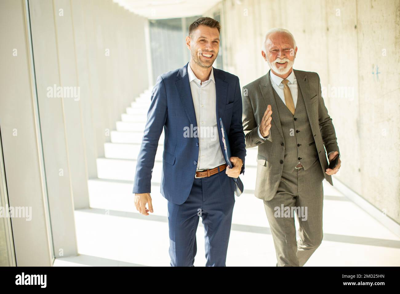 Handsome mature businessman and his young colleague discussing financial report Stock Photo