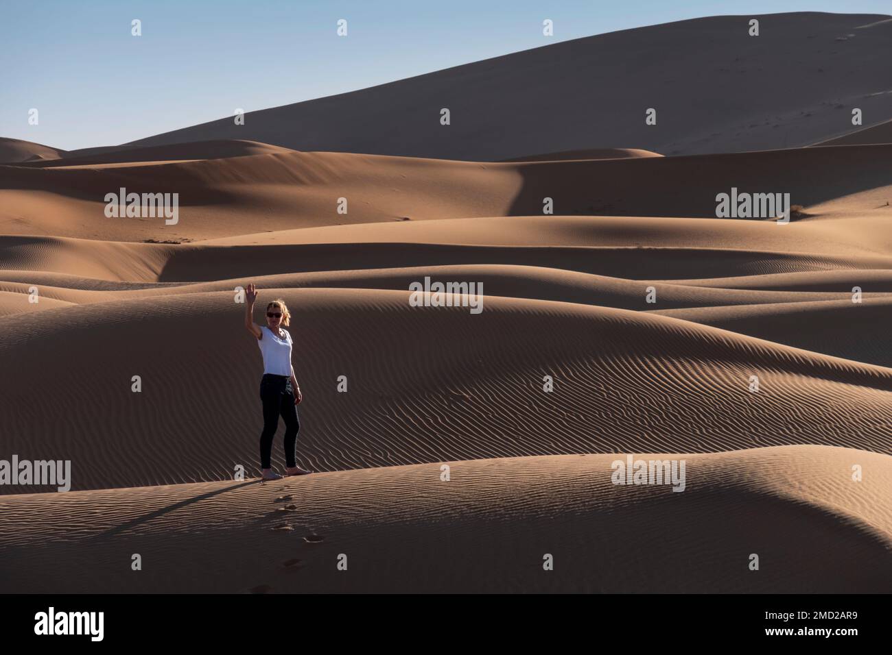 Woman Tourist in the Sand Dunes of Erg Chebbi, Sahara Desert, Morocco, North Africa Stock Photo