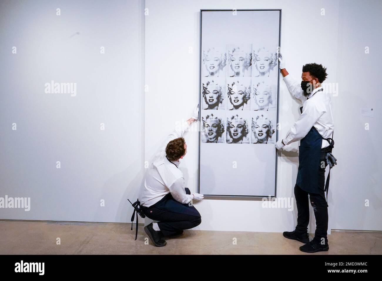 Art hangers adjust Andy Warhol's "Nine Marilyns" on display at Sotheby's auction house during a