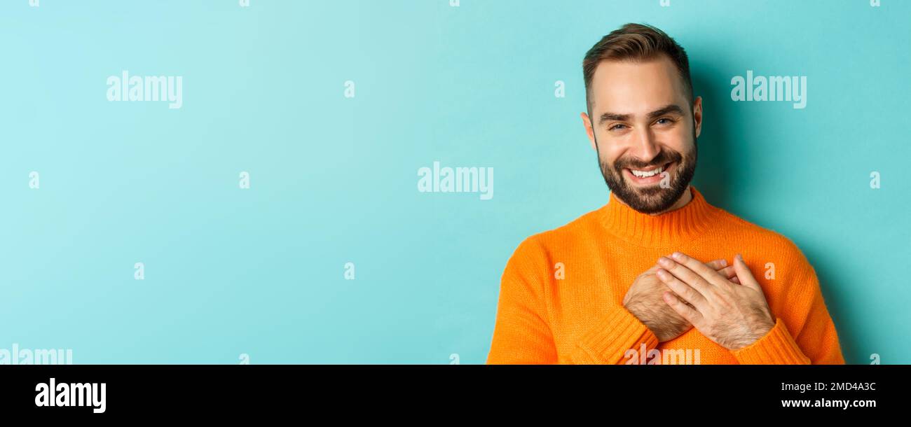 Close-up of handsome young man saying thank you, holding hands on heart