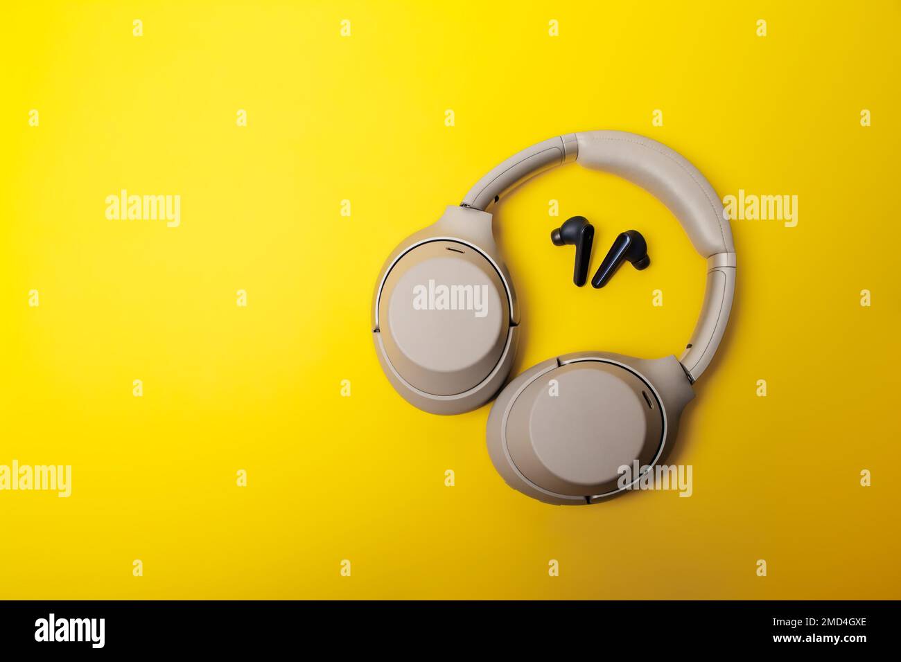 Light gray wireless onear headphones and blue inear wireless headphones on a yellow background