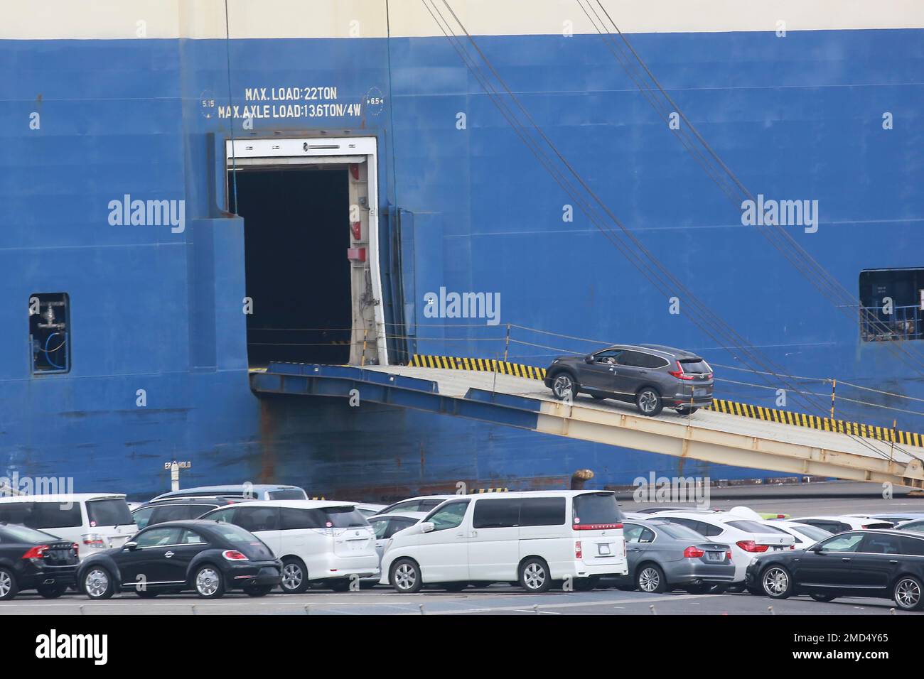 Cars for export are loaded onto a cargo ship at a port in Yokohama ...