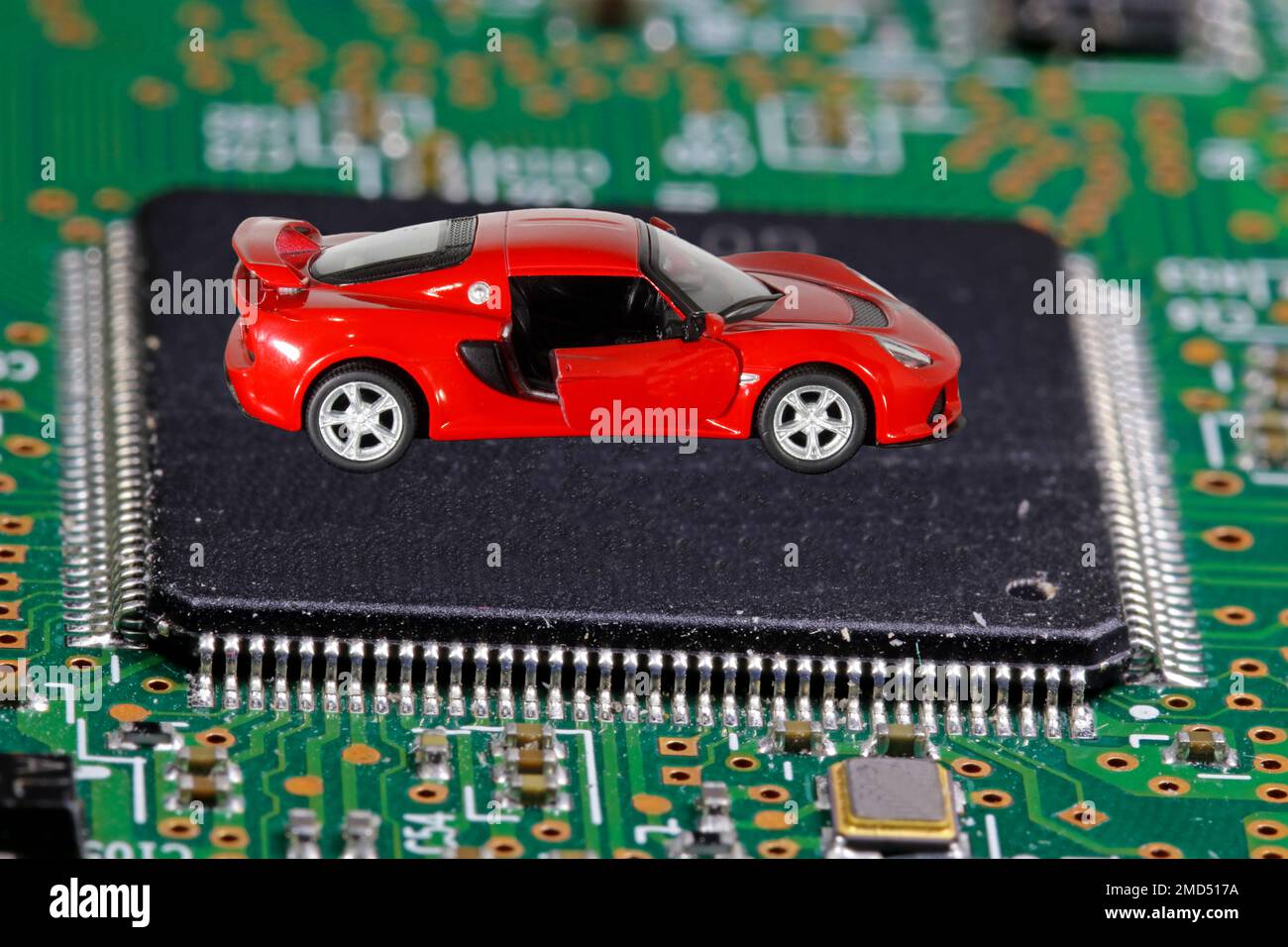 The red car stands on the microprocessor. The concept of a shortage of chips in the automotive industry. Stock Photo