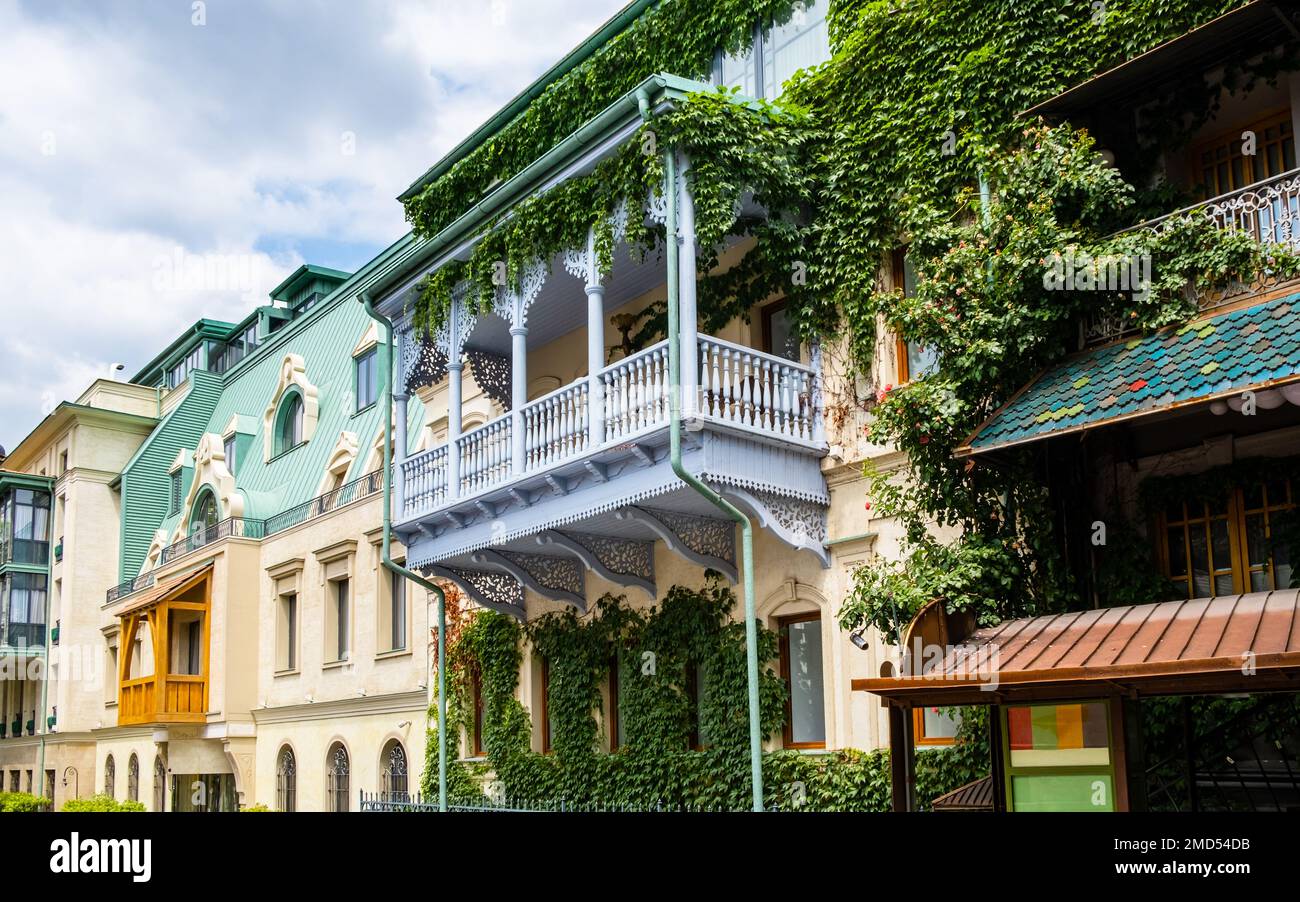 Carved wooden balcony and colorful buildings in historical Tbilisi, Georgia. Traditional decoration of Georgian house in Tiflis old town. Ivy on wall Stock Photo