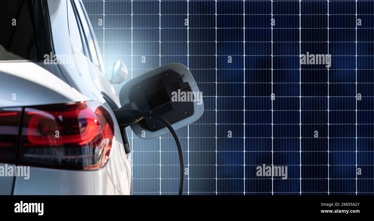 Close up of electric car with a connected charging cable on the background of solar panels  Stock Photo