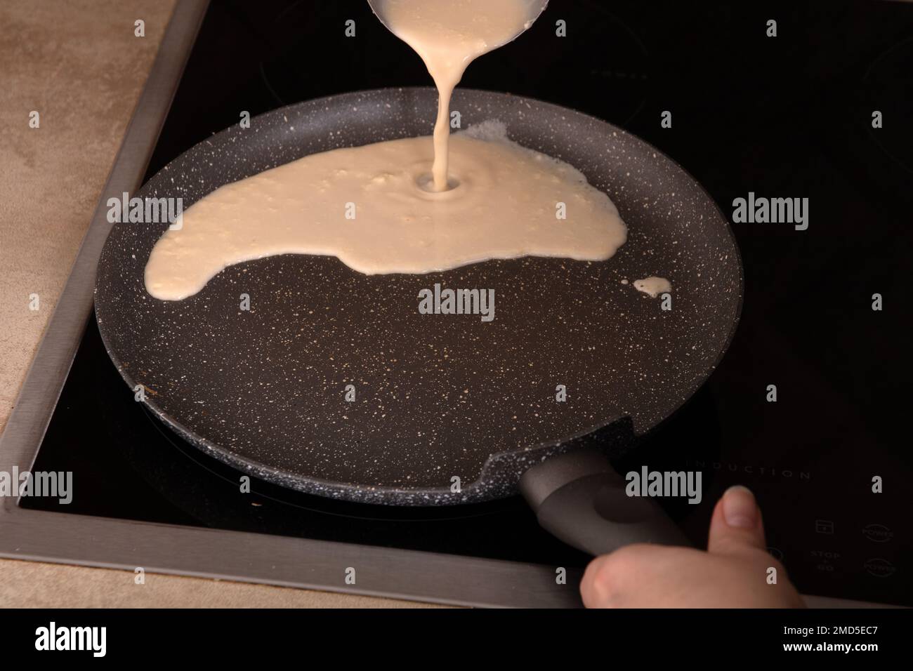 photo batter for thin pancakes poured on a hot pan on the stove Stock