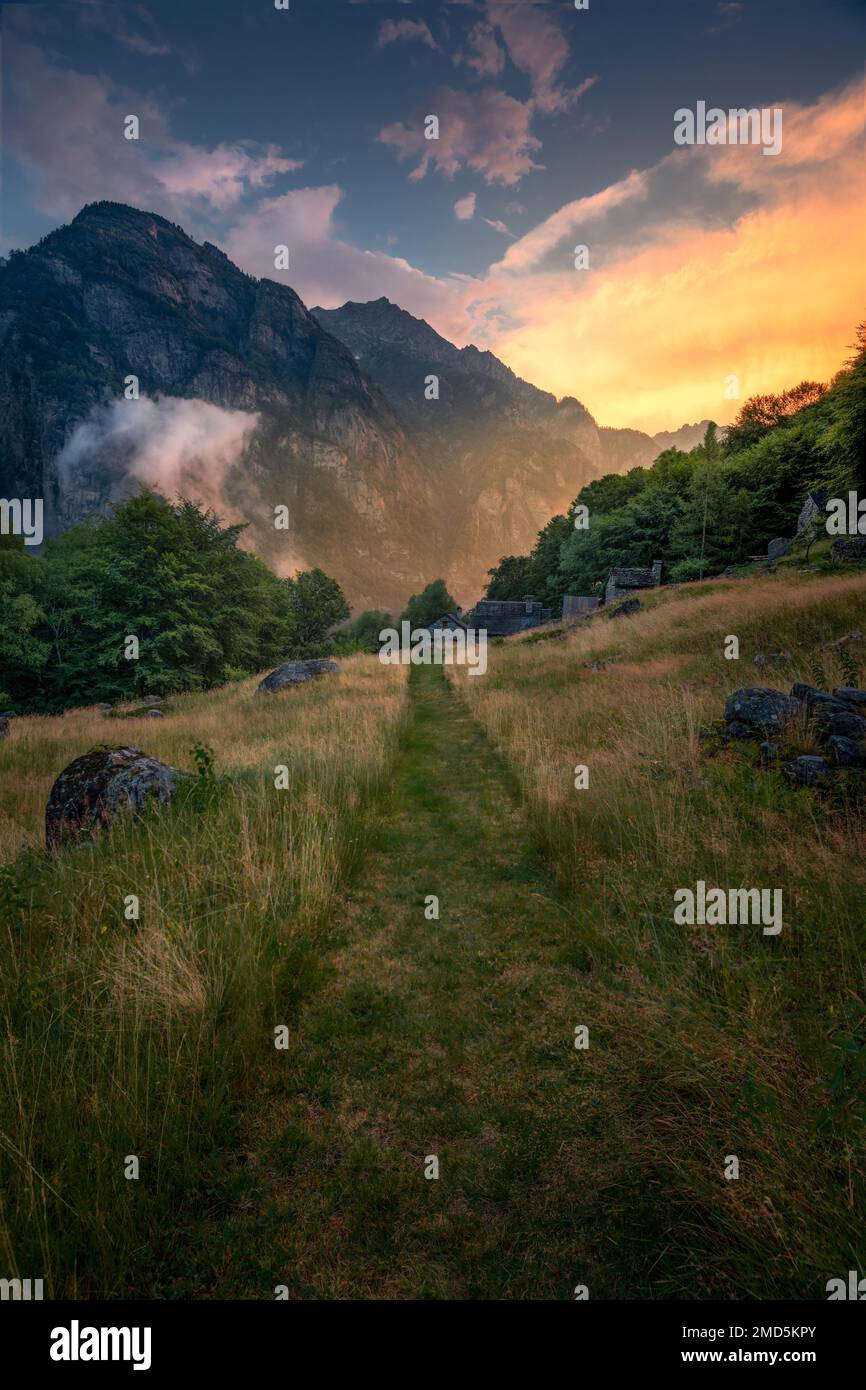 A green hiking trail during a sunset between mountains Stock Photo - Alamy