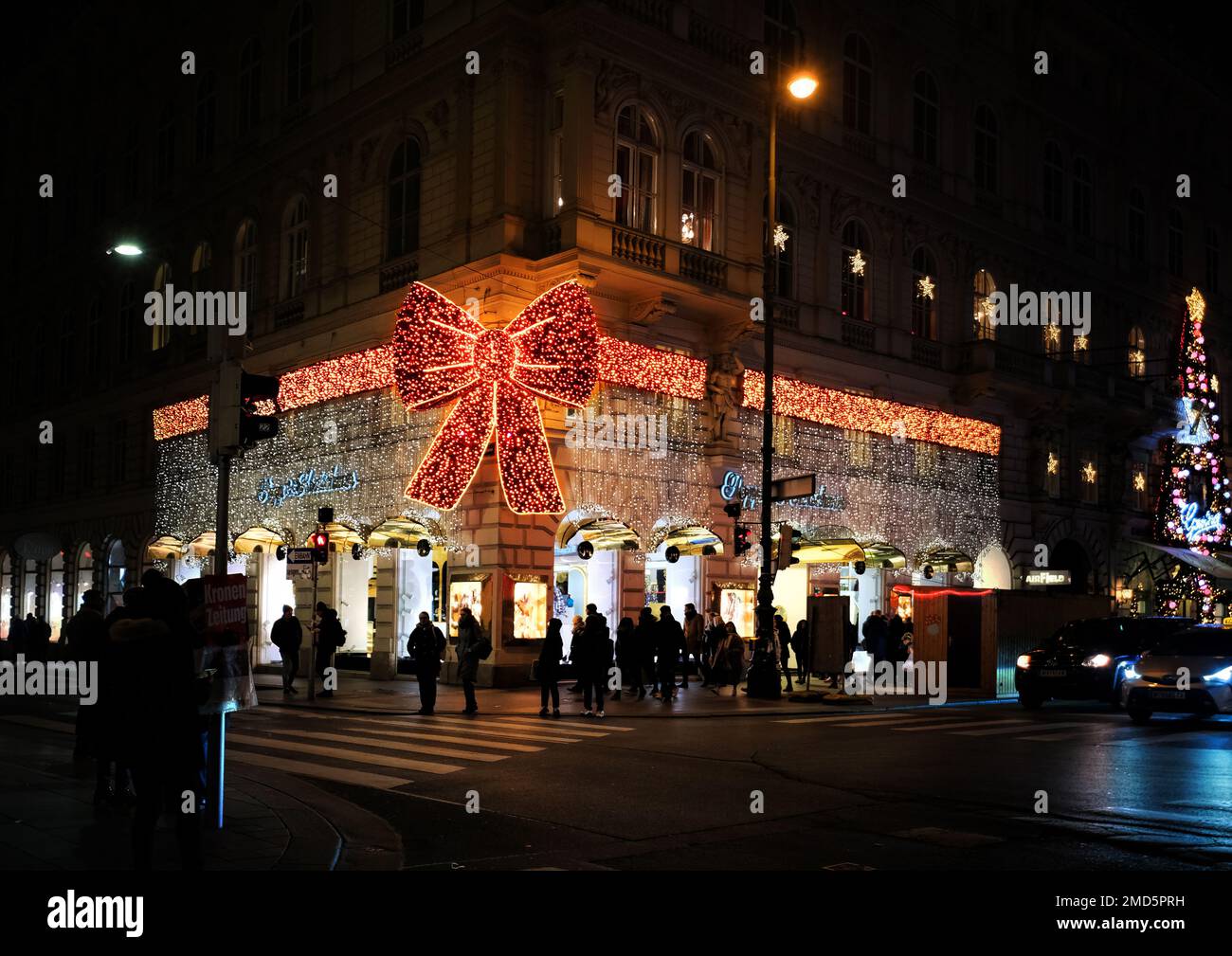 Vienna, Austria, Dec. 2019: Celebratory design of the street in the form of a bow and People walking, decorated and illuminated for christmas Stock Photo