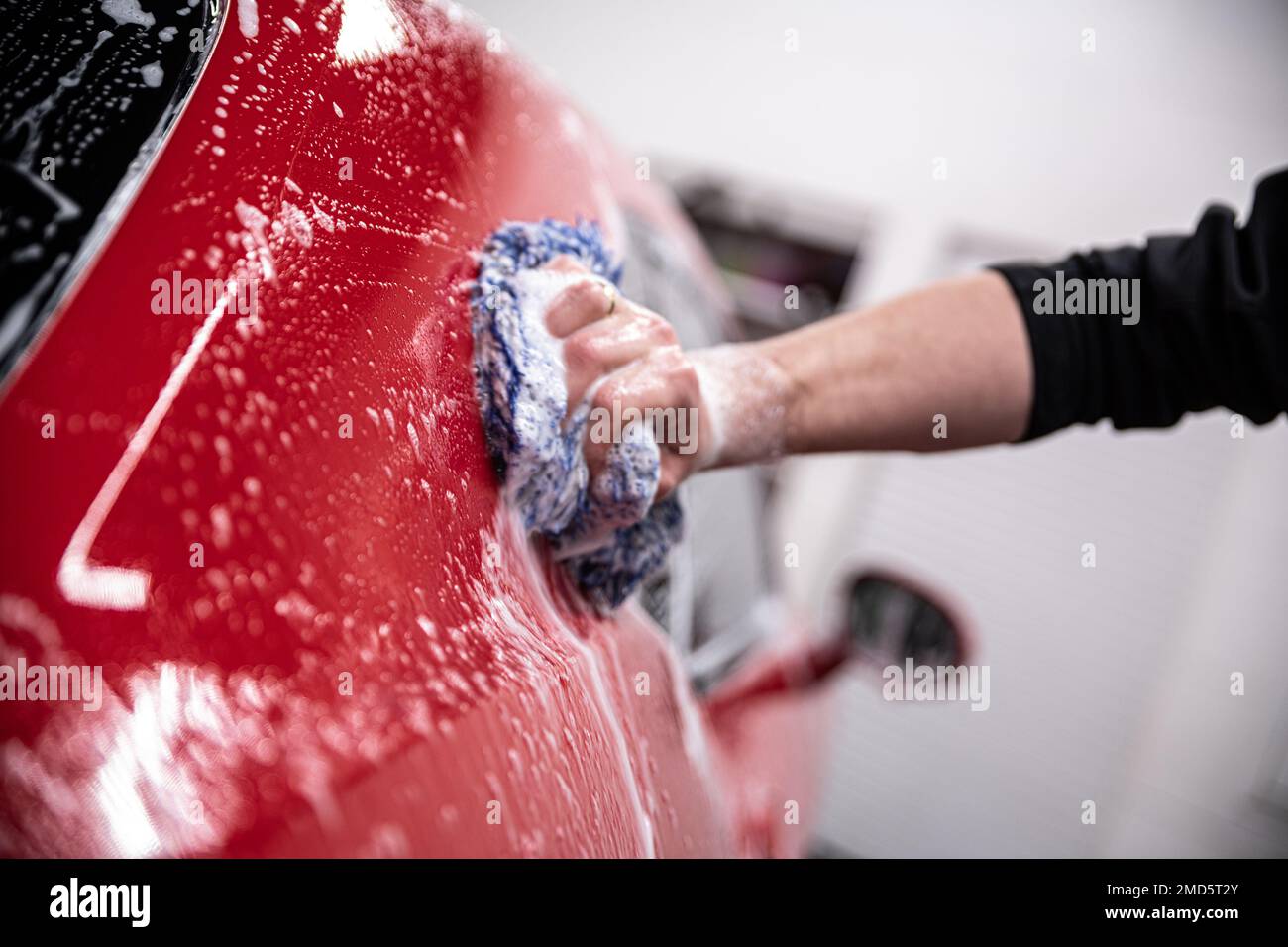 Employee of a manual car wash carefully washes the car with a sponge
