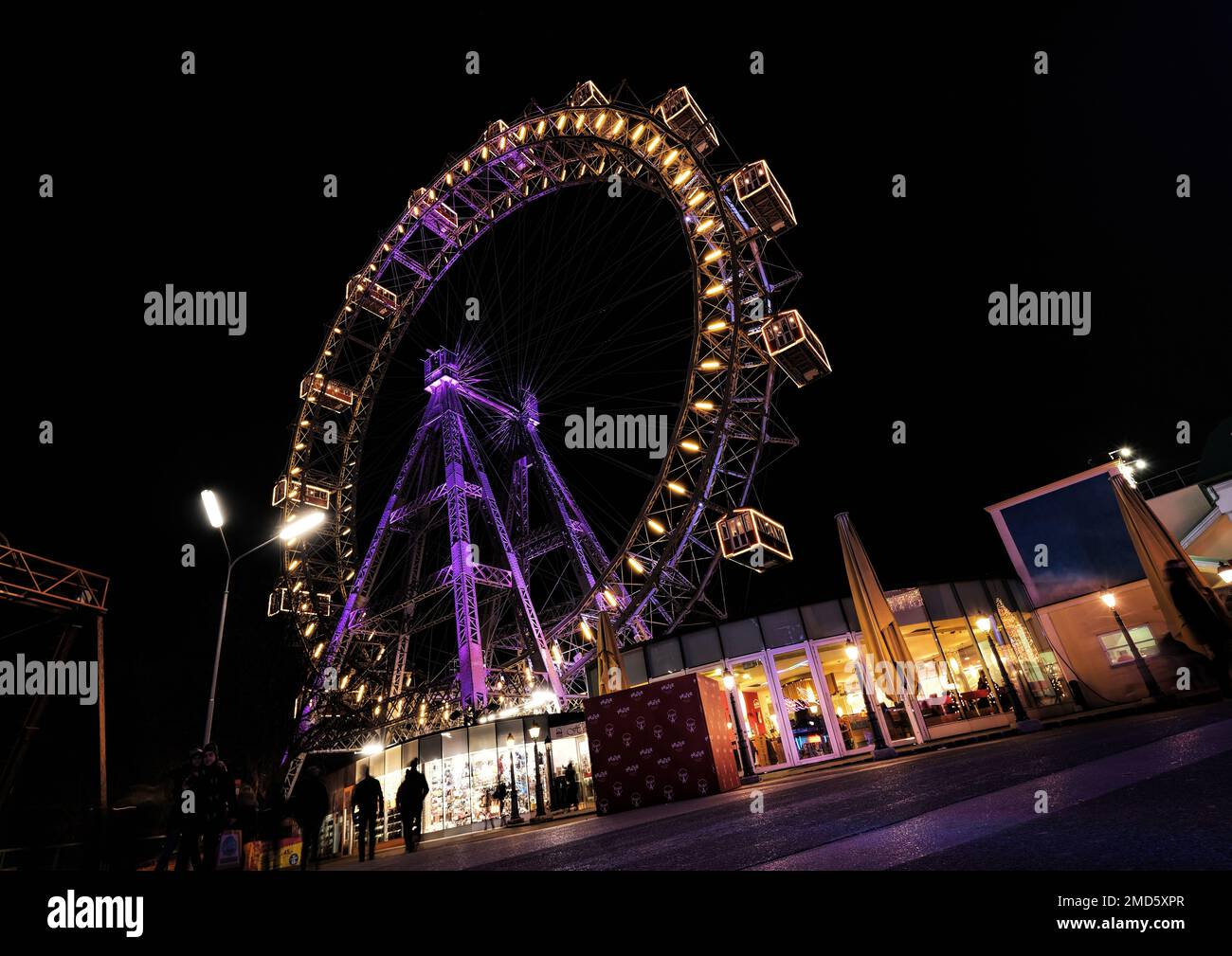 Vienna, Austria, Dec. 2019: View of popular Ferris wheel with colorful illuminated rim at night in amusement park Prater (Wurstelprater) Stock Photo