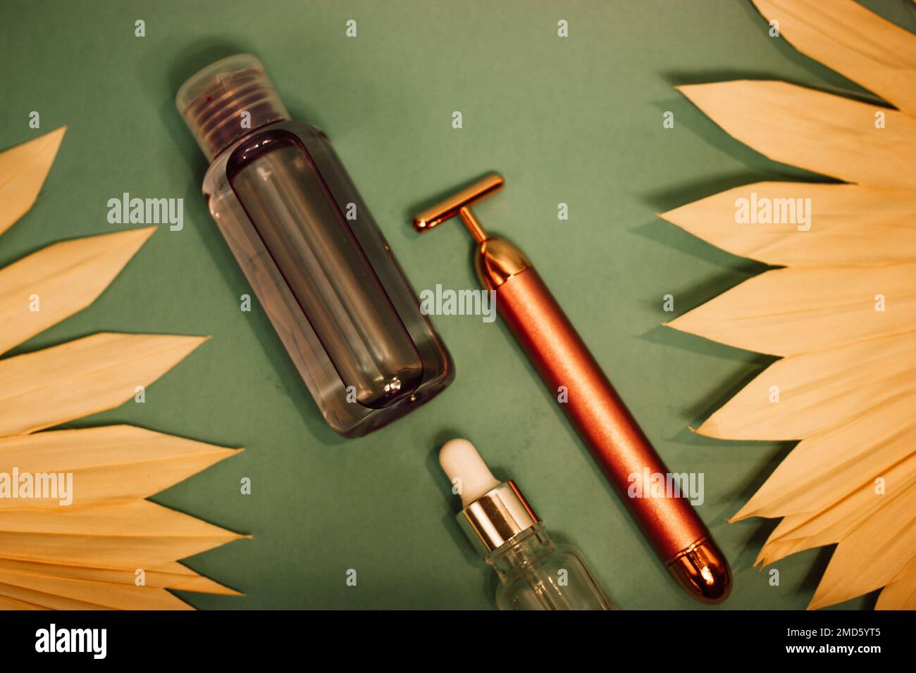 Vibrating golden facial massager, glass jar with oil dropper for massage on  dark green background flatly. Female body skin care. Luxury beauty tool. P  Stock Photo - Alamy