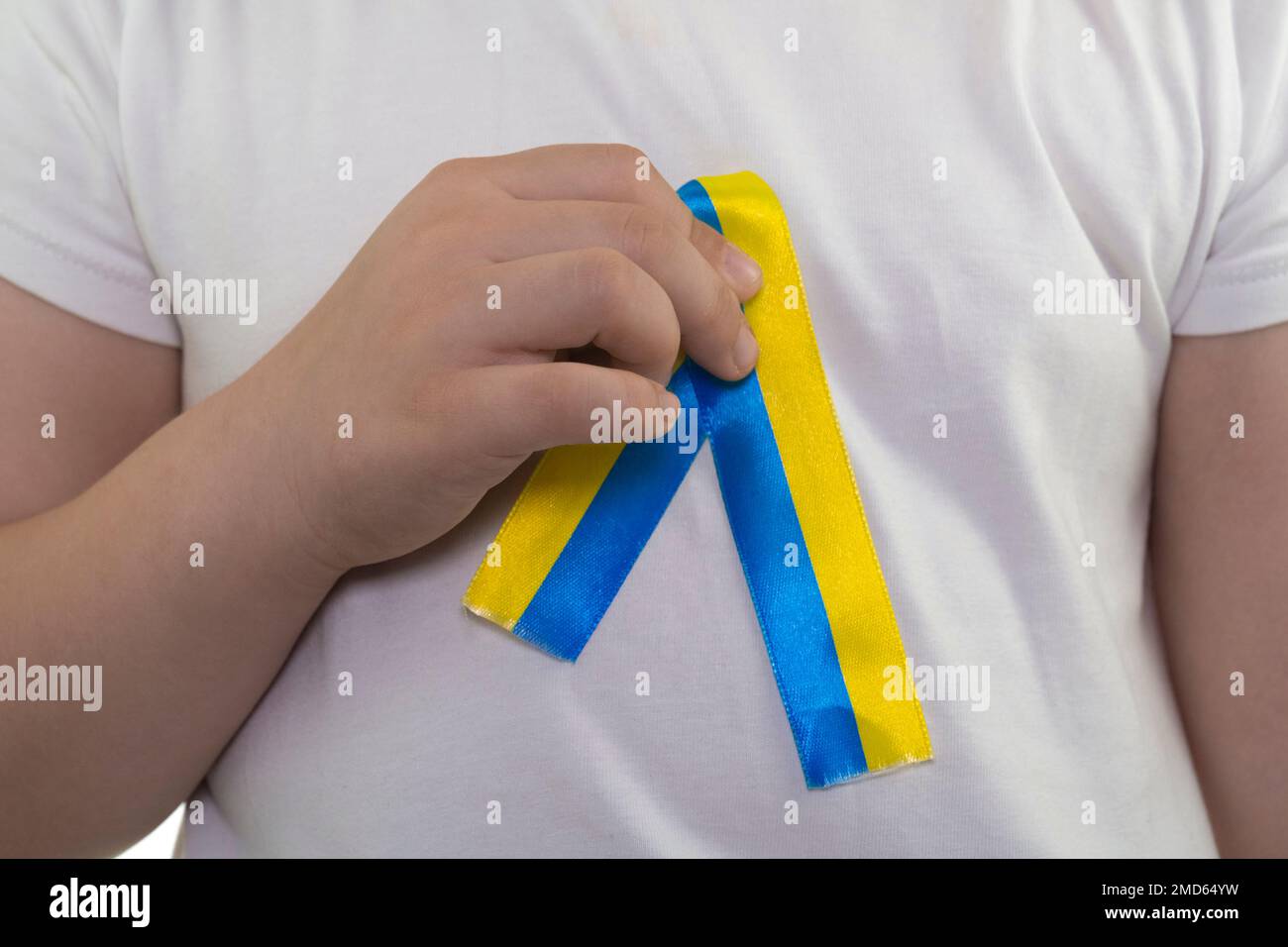 Girl in a white T-shirt with a loop of yellow-blue textile ribbon hanging on it (close-up). State flag of Ukraine. National symbol of Ukraine. Patriot Stock Photo
