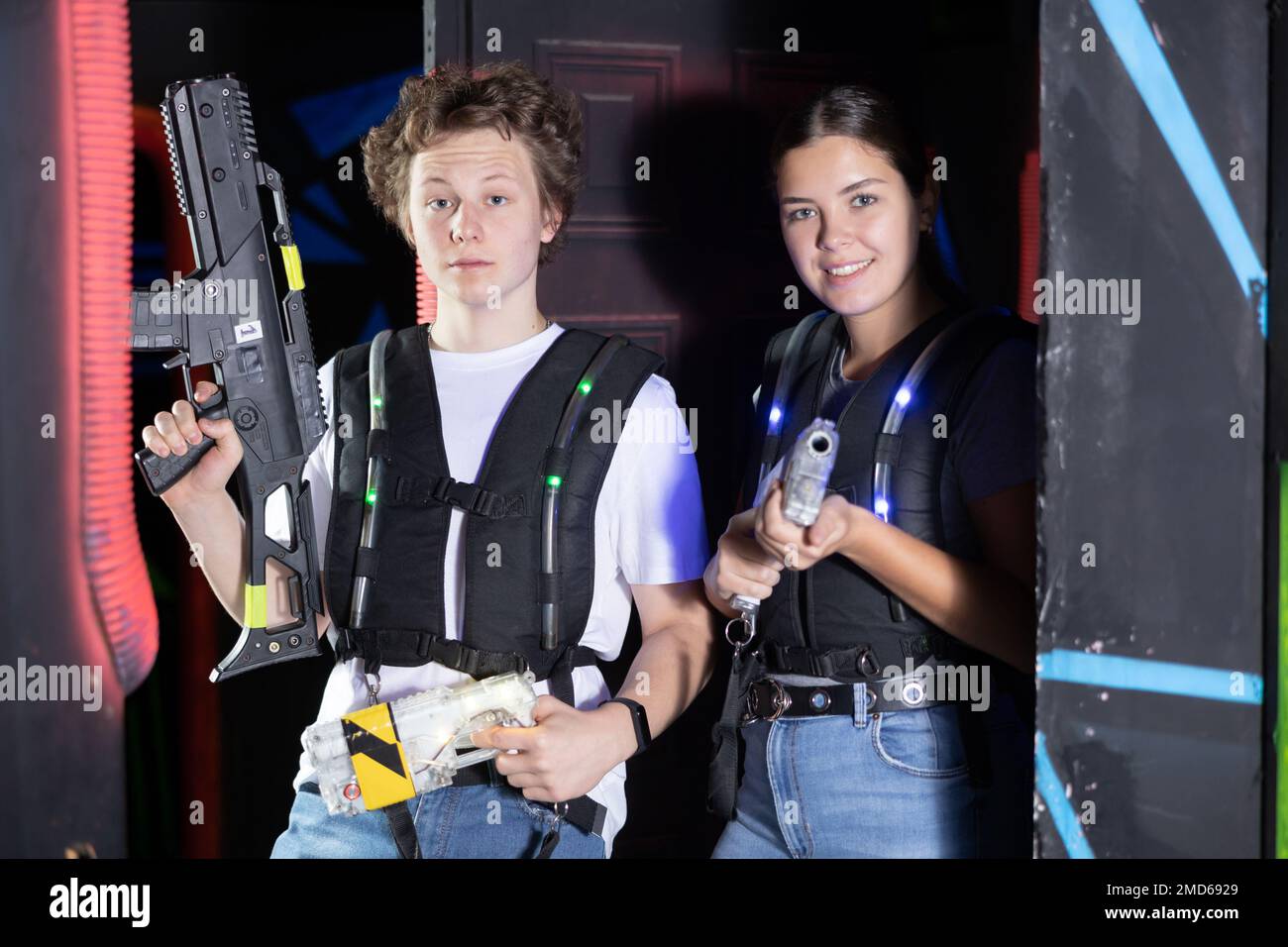 Portrait of woman and man holding laser gun in arena, playing laser tag