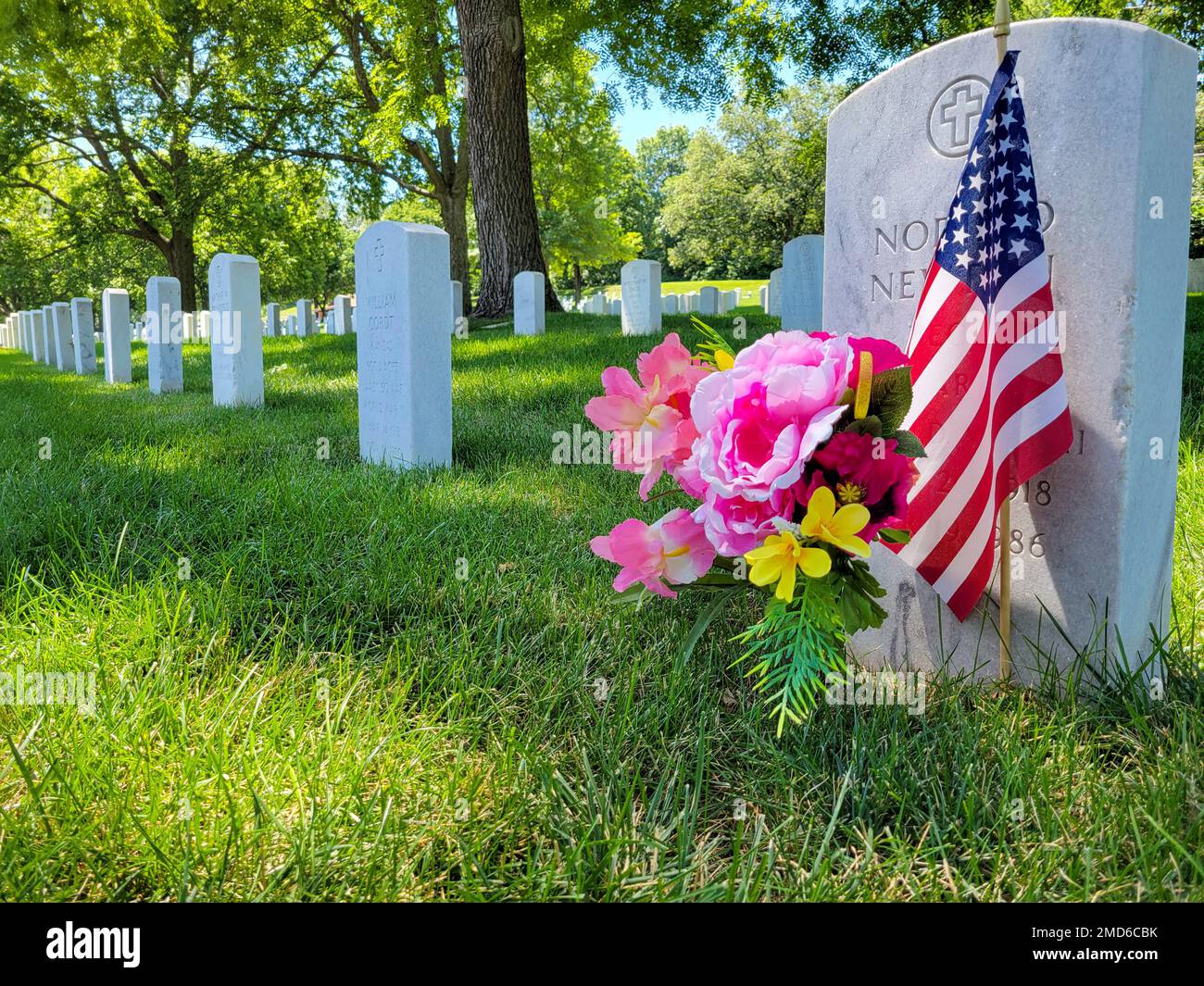 Flowers and a U.S. Flag are placed in front of a gravestone at the Fort ...