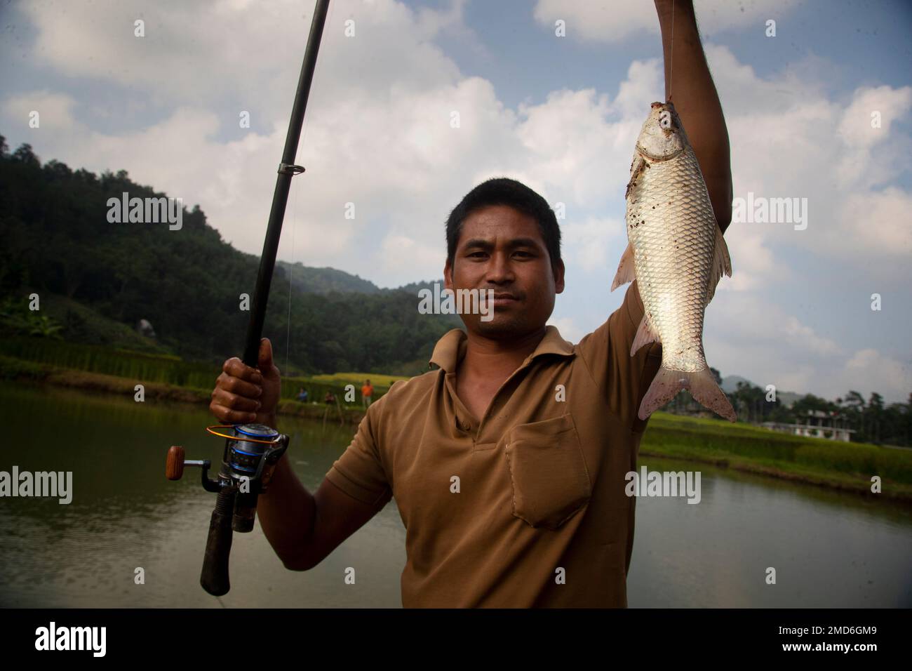 A Khasi tribal man shows his catch after fishing in a pond in