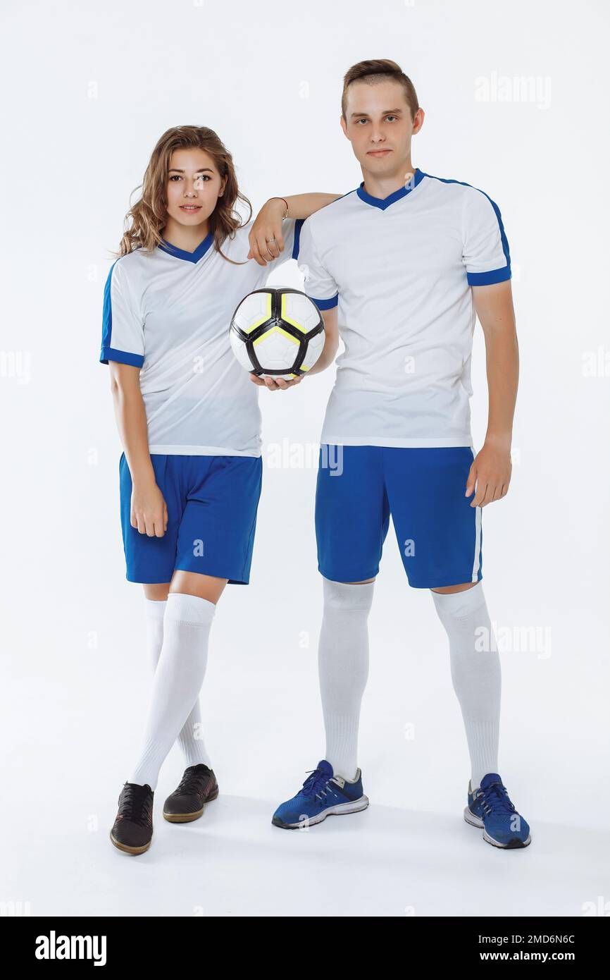 Girl and man in soccer uniforms holding a soccer ball on a white background Stock Photo