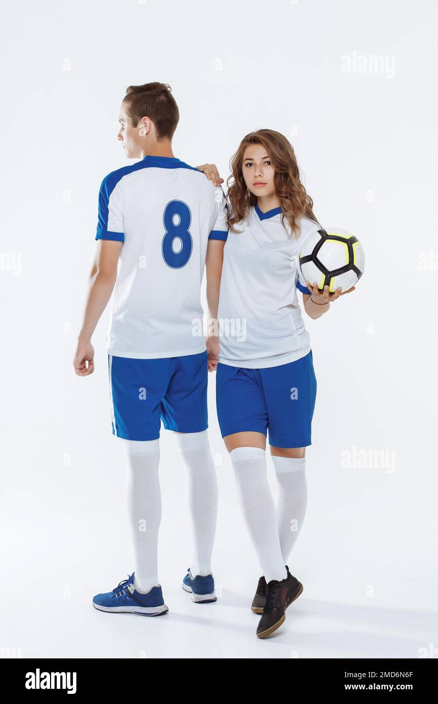 Girl and man in soccer uniforms holding a soccer ball on a white background Stock Photo