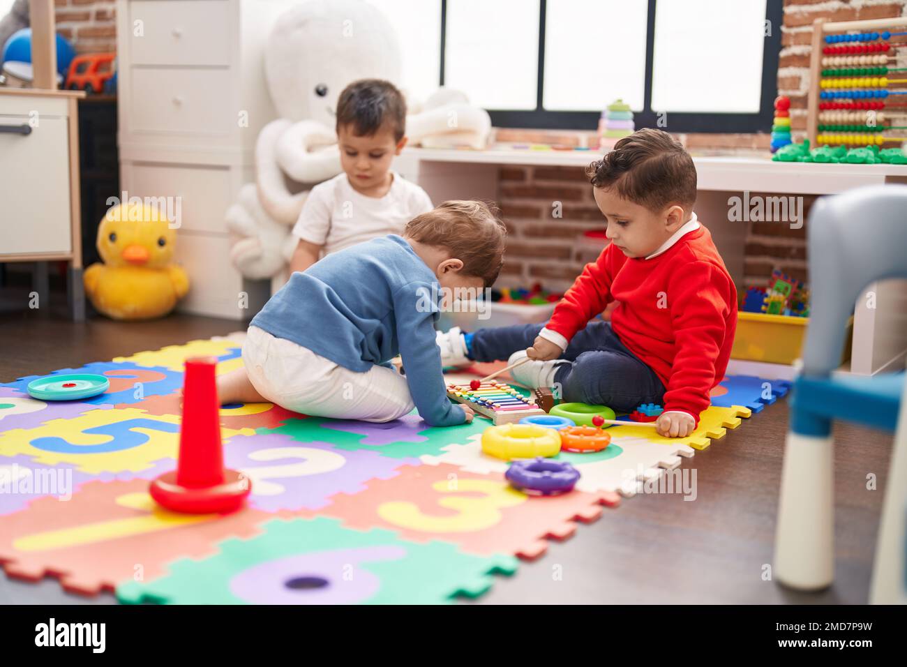 Group of kids playing xylophone sitting on floor at kindergarten Stock