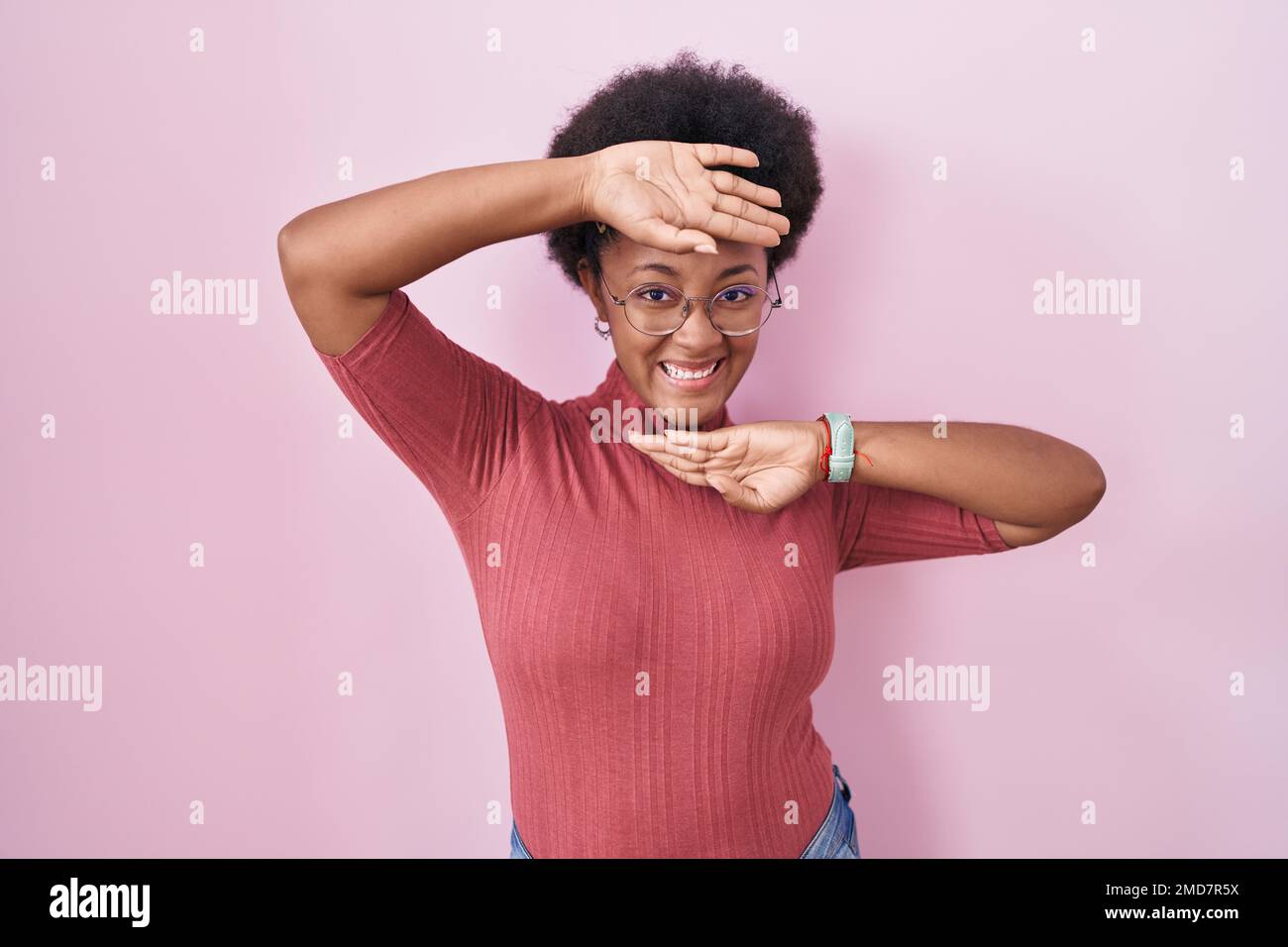 Beautiful african woman with curly hair standing over pink background ...