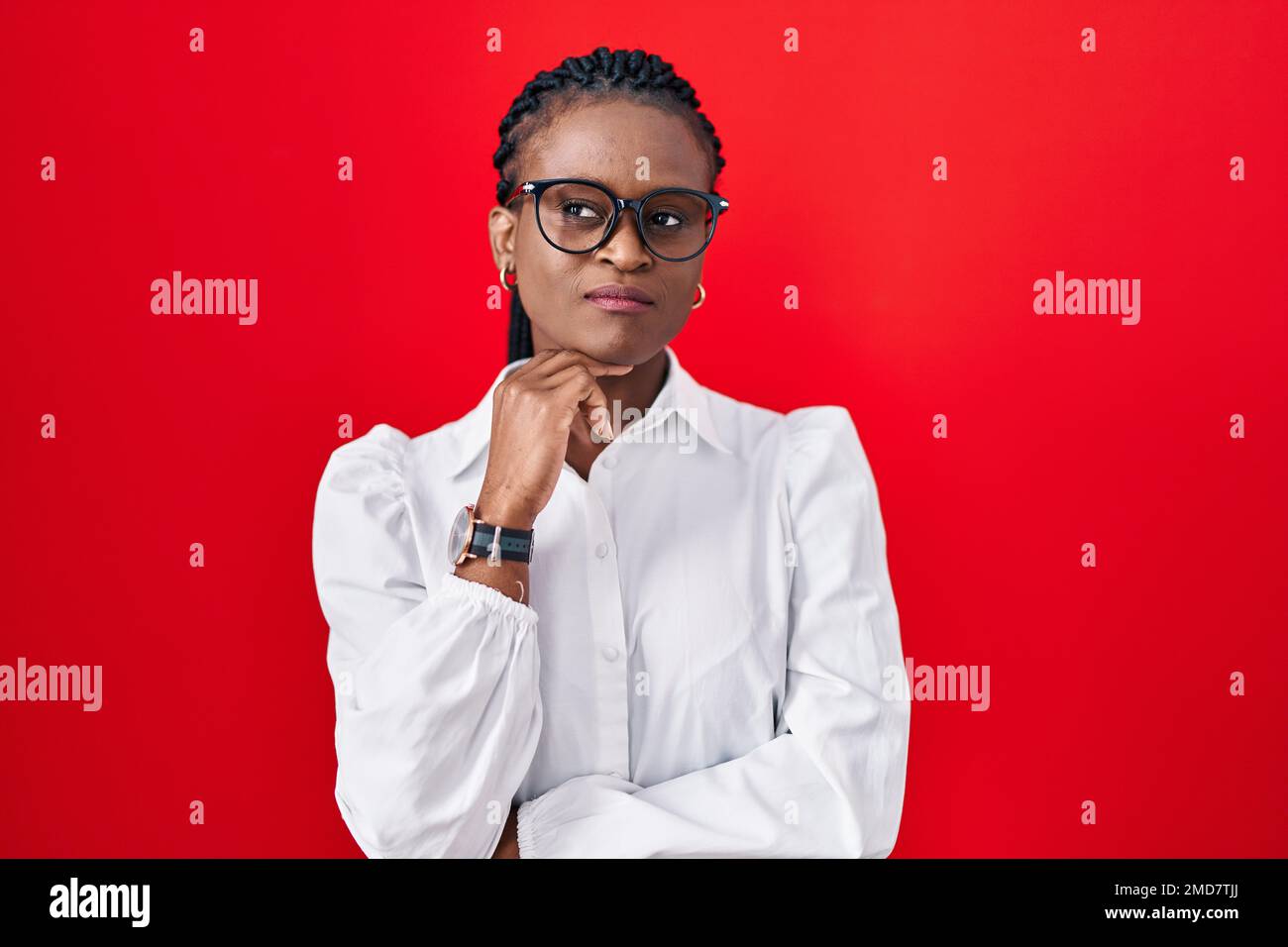 African woman with braids standing over red background with hand on ...
