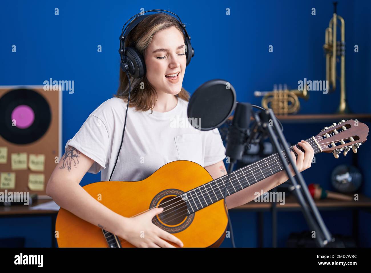 Young woman musician singing song playing classical guitar at music ...