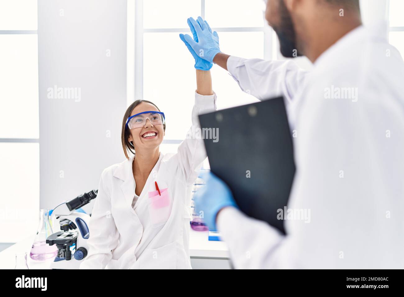 Man and woman scientist partners holding clipboard high five raised up ...