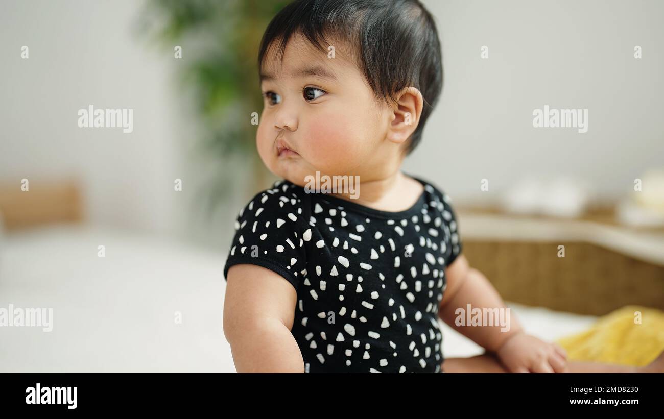 Adorable hispanic baby sitting on bed at home Stock Photo - Alamy