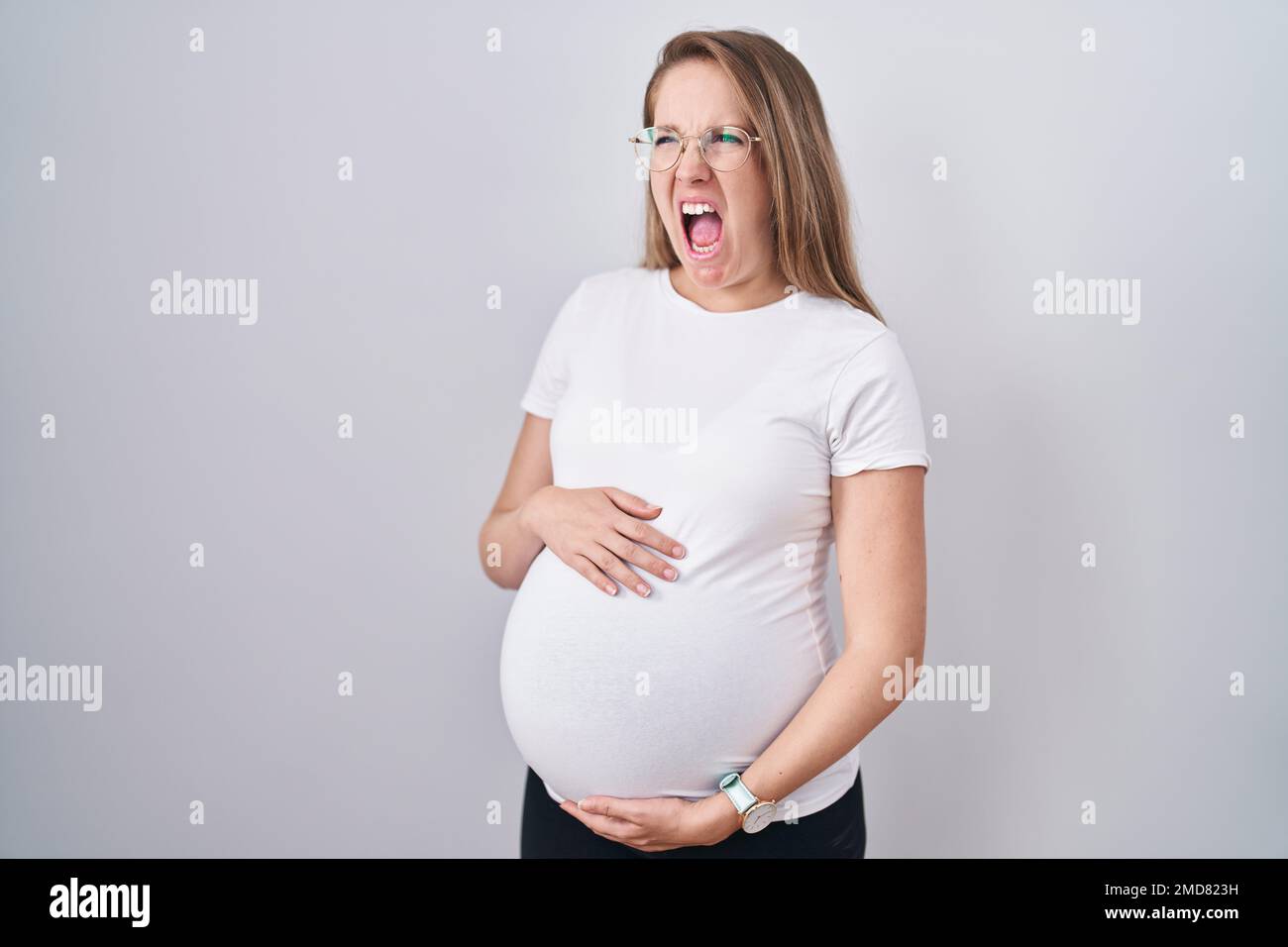 Young pregnant woman expecting a baby, touching pregnant belly angry ...