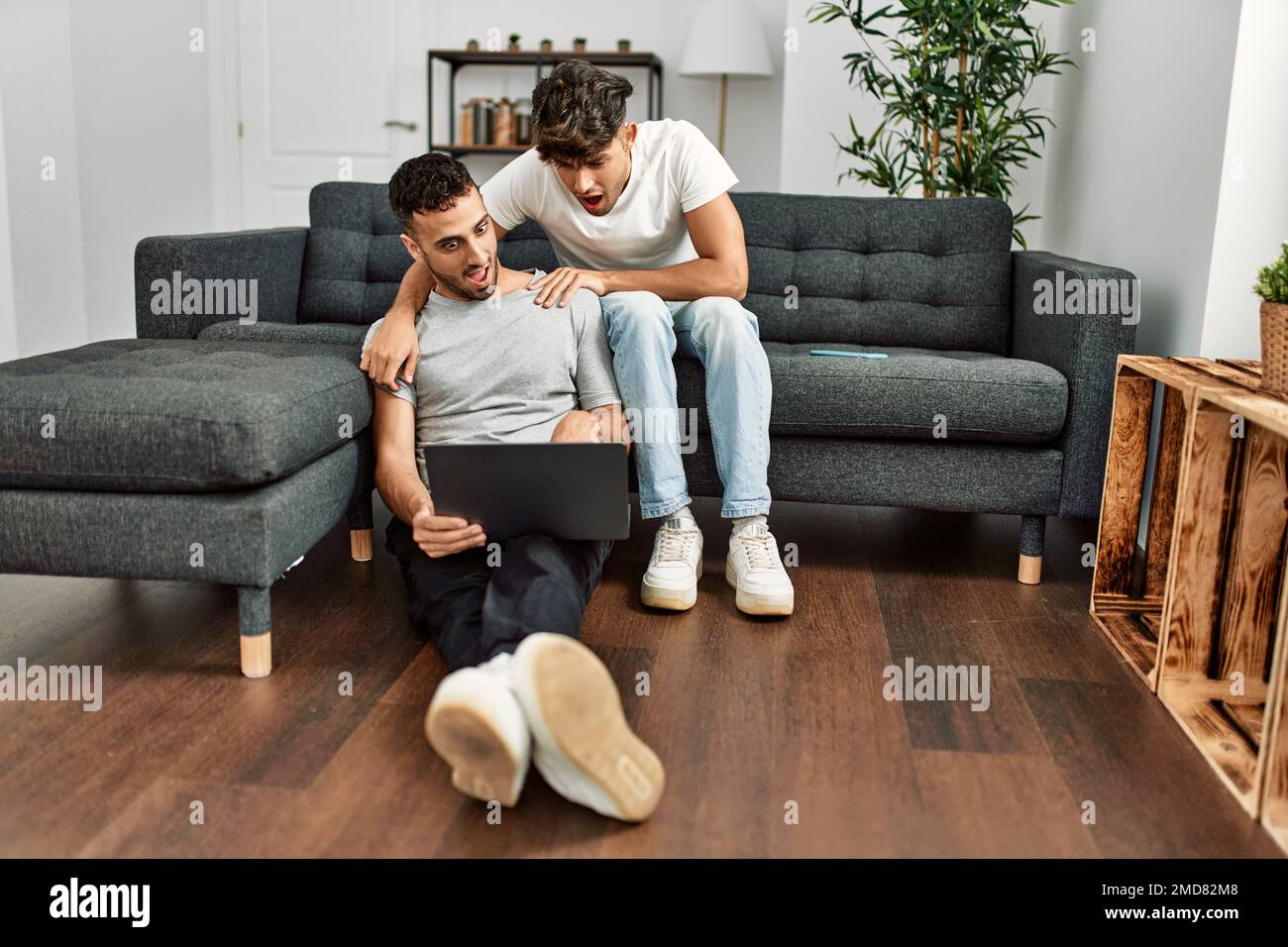 Two hispanic men couple using laptop hugging each other at home Stock ...