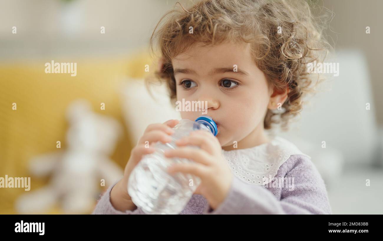 Adorable hispanic girl drinking water standing at home Stock Photo