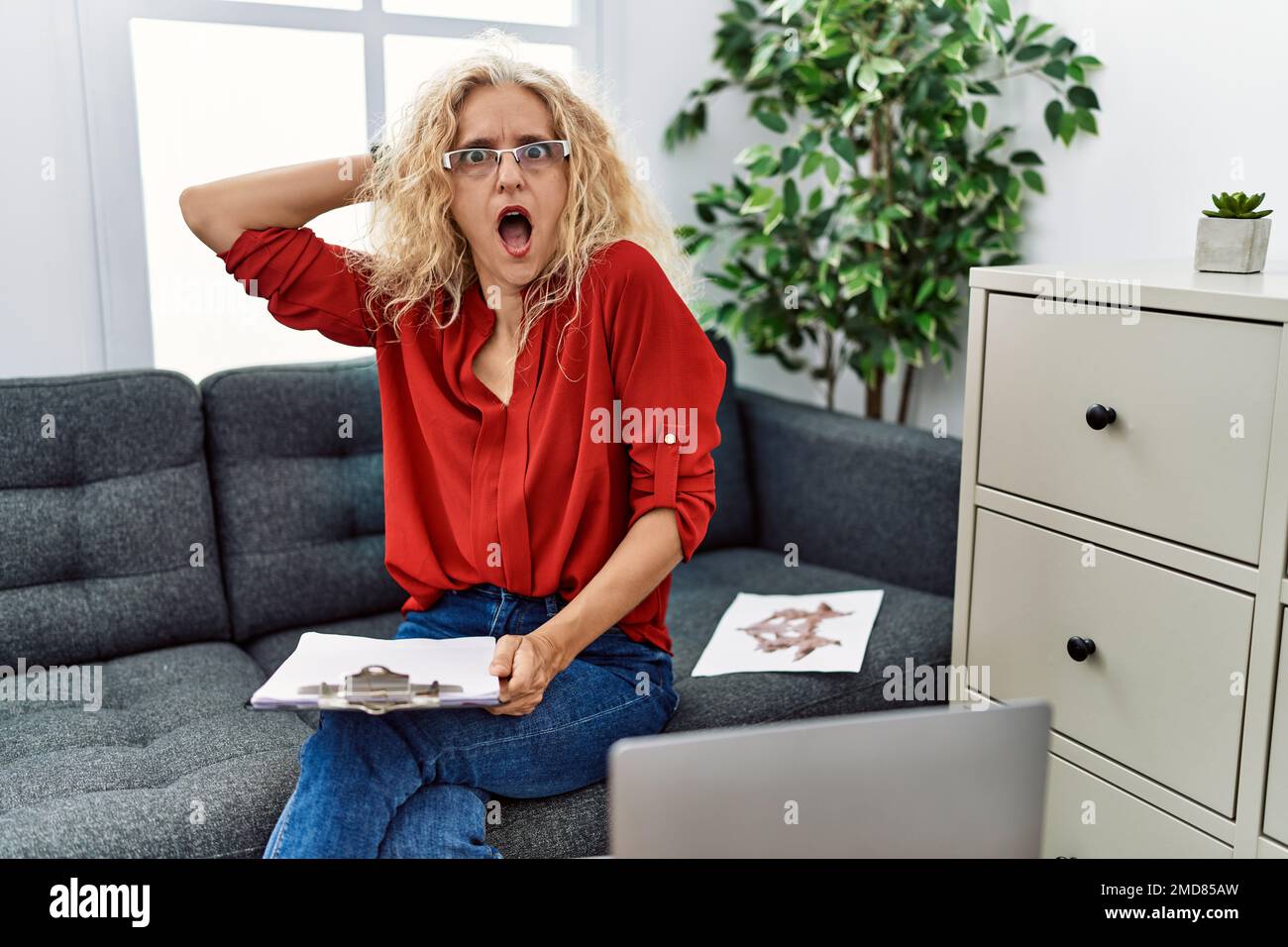Middle age psychologist woman at consultation office crazy and scared with  hands on head, afraid and surprised of shock with open mouth Stock Photo -  Alamy