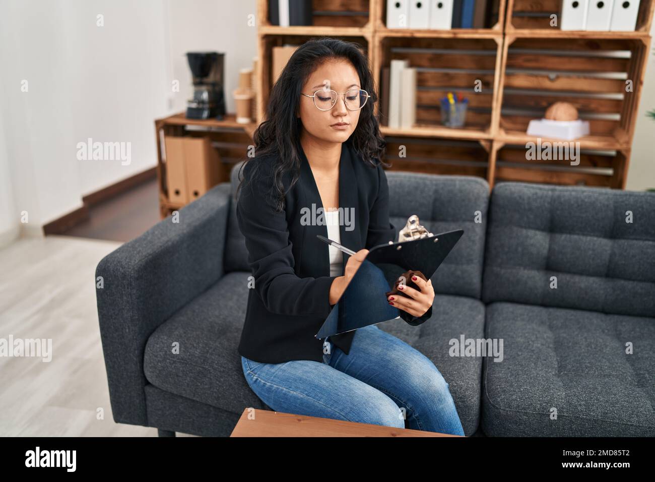 Young chinese woman psychologist writing on clipboard at clinic Stock Photo Alamy