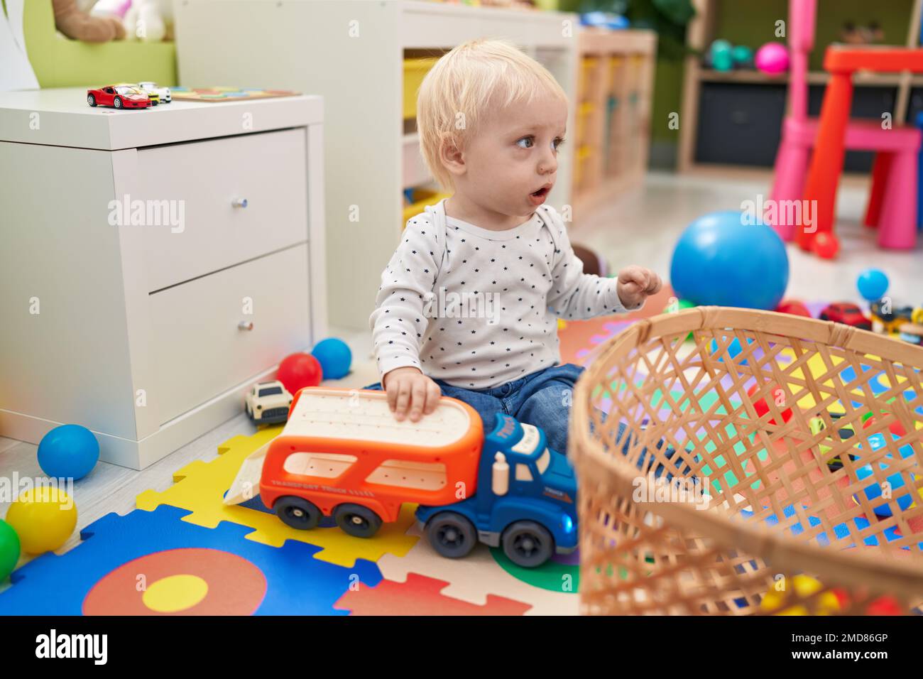 Adorable blond toddler playing with cars toy sitting on floor at ...