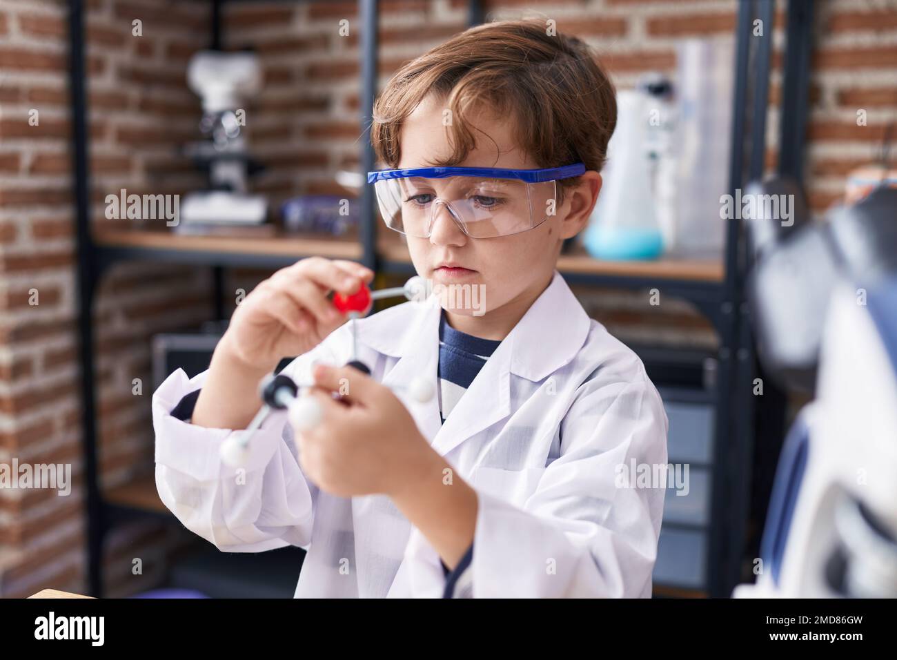 Adorable hispanic boy student looking molecules at laboratory classroom ...