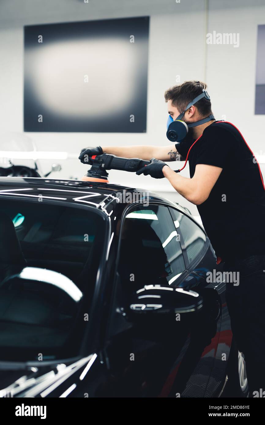 Man polishing car paintwork. Vertical shot. Professional car detailing