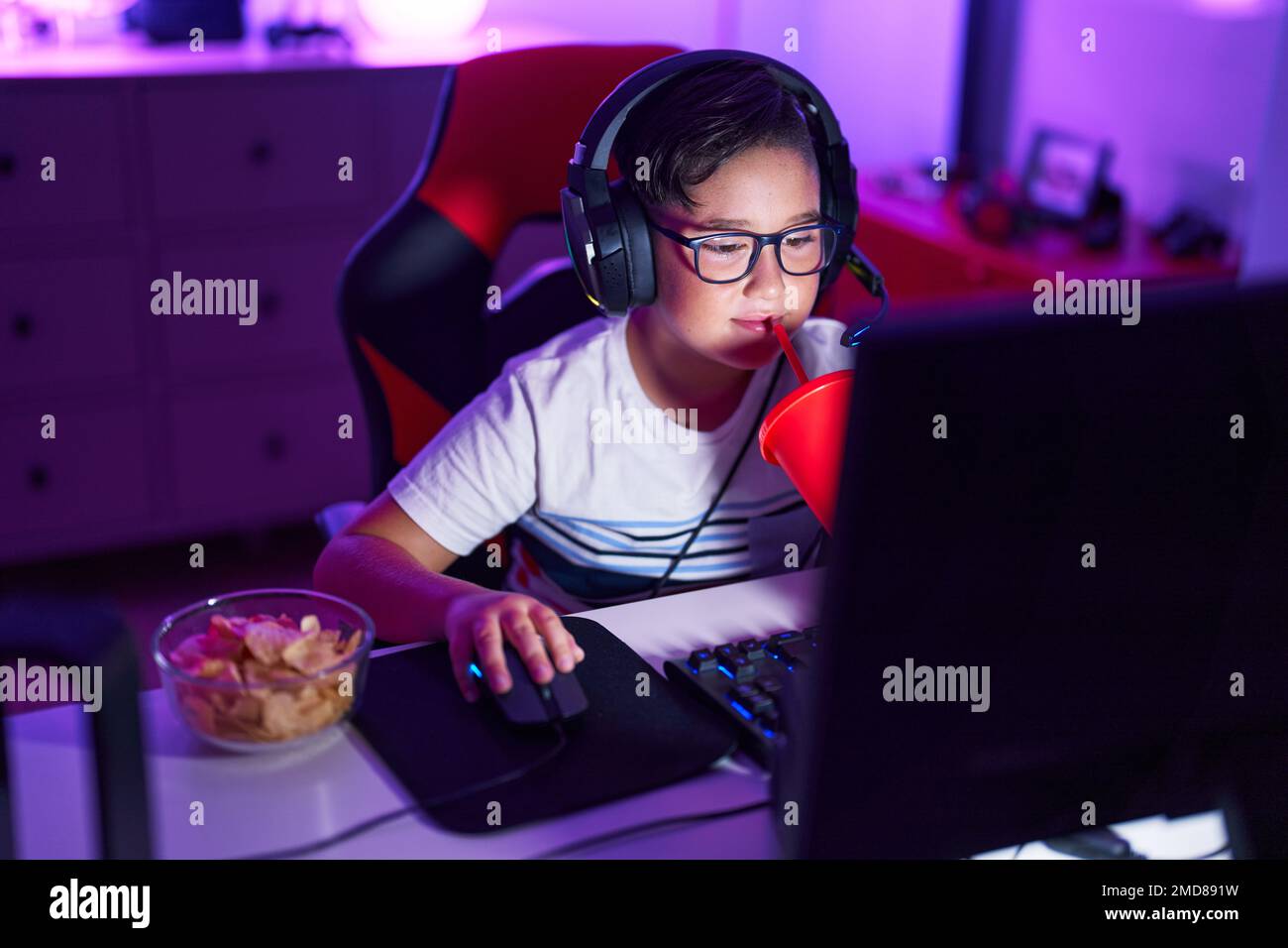 Adorable hispanic boy streamer playing video game drinking beverage at ...