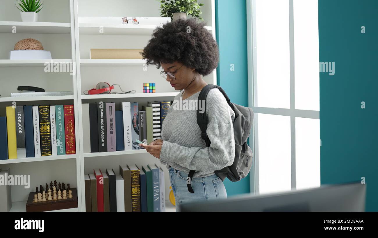 African american woman student using smartphone at library university ...