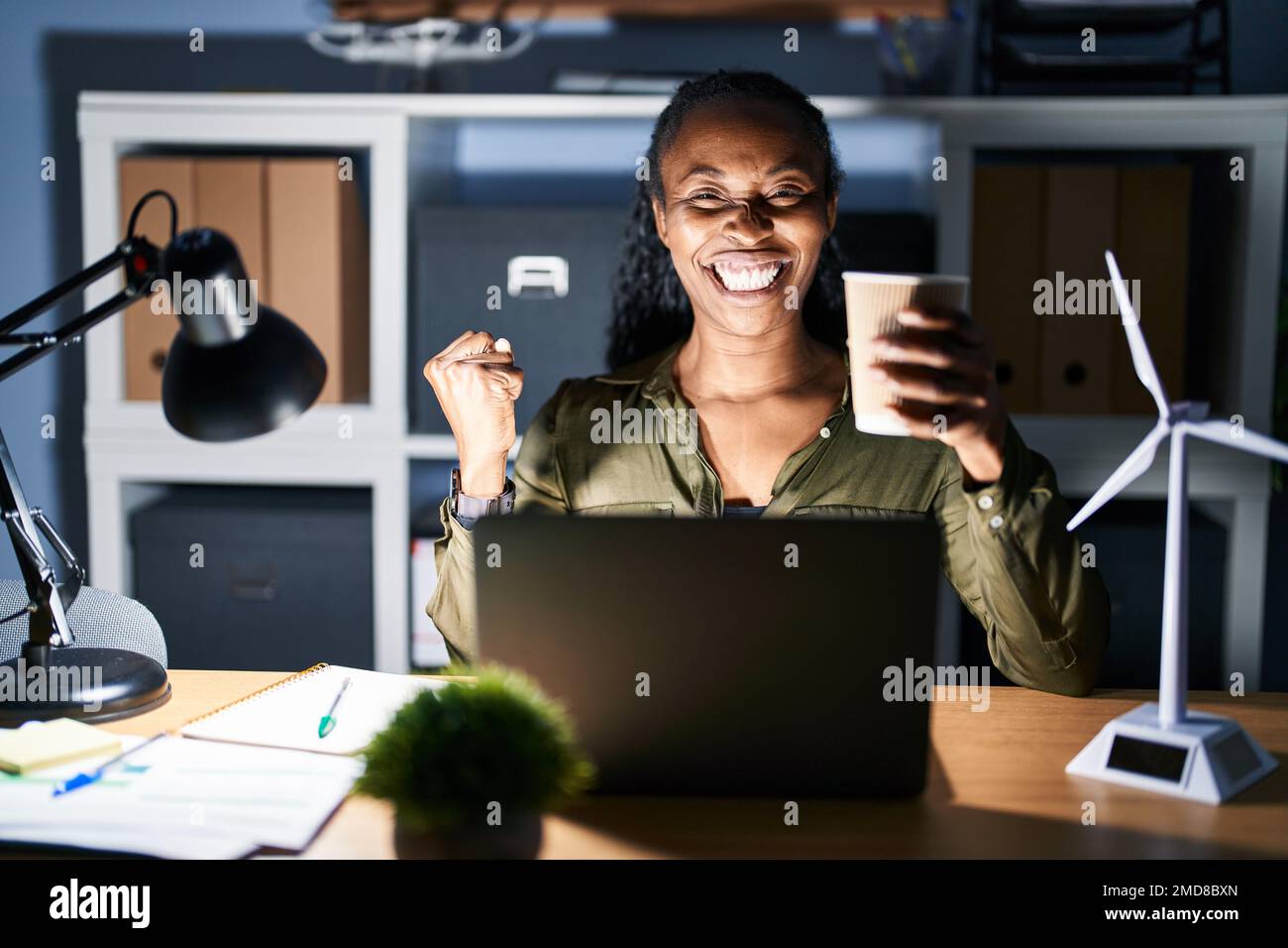African woman working using computer laptop at night very happy and ...