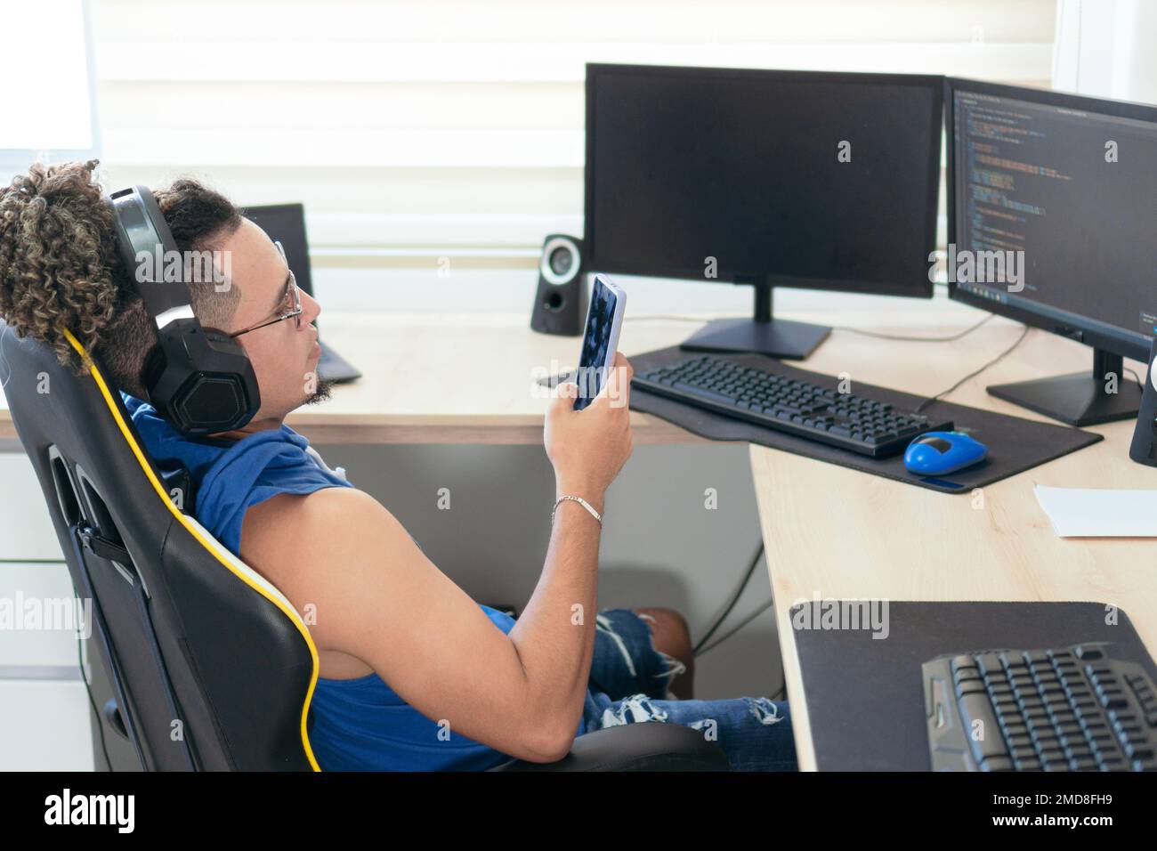 Computer programmer sitting in his office and typing on his cell phone. Stock Photo