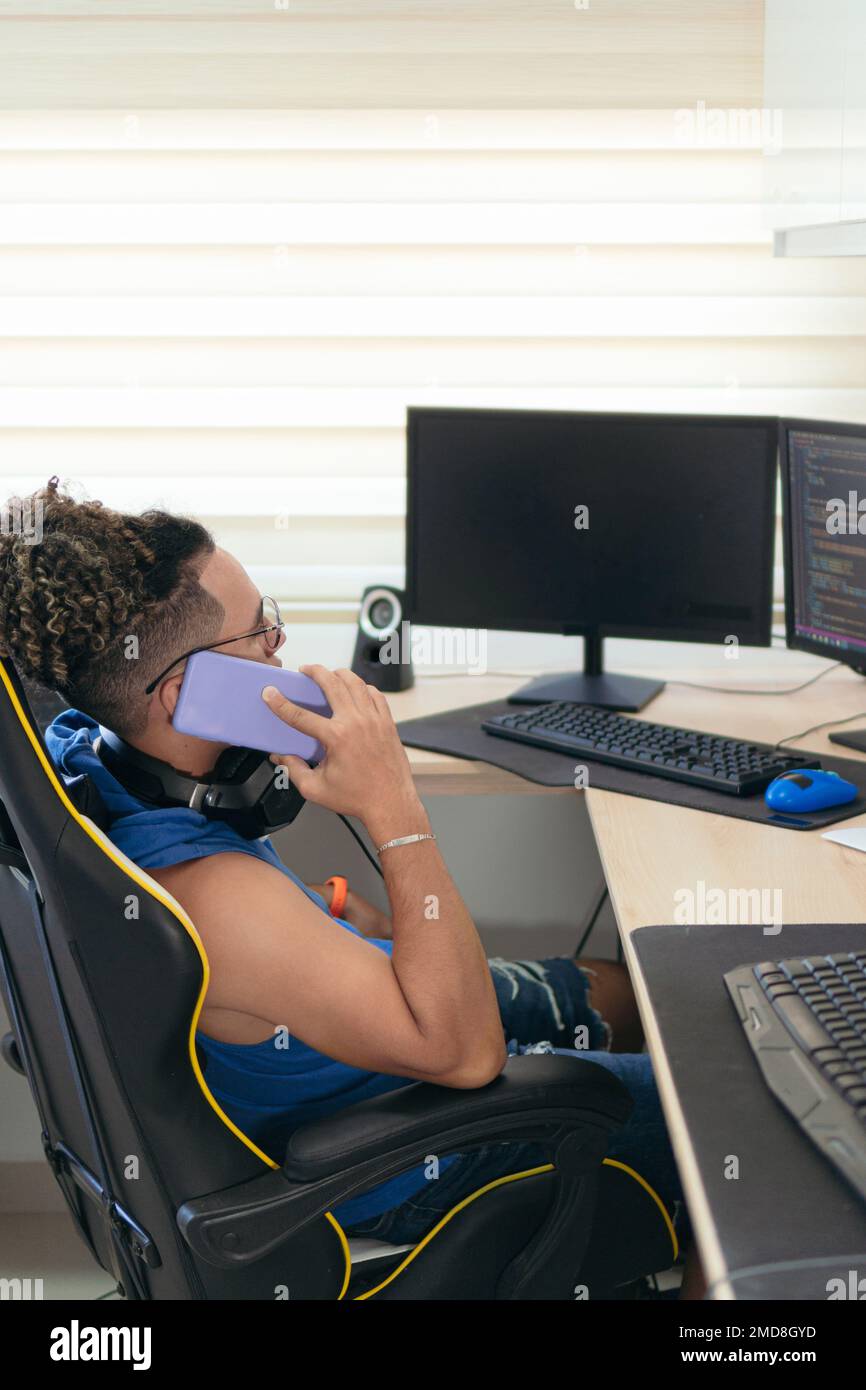 Computer programmer talks on cell phone while working from home Stock Photo