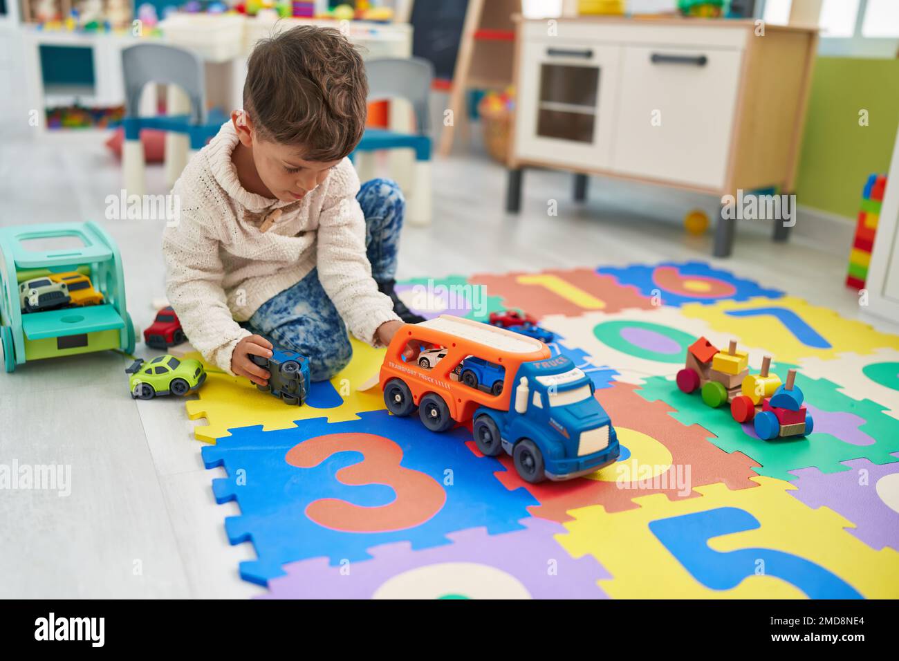 Adorable hispanic toddler playing with cars toy sitting on floor at ...