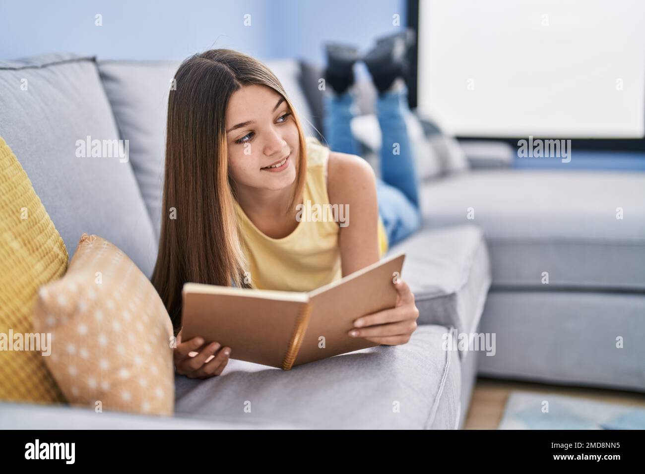 Adorable girl reading book lying on sofa at home Stock Photo - Alamy