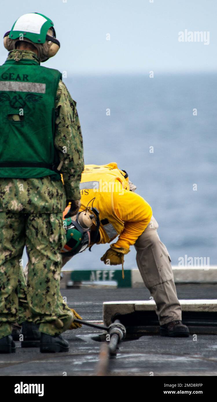 220714-N-DW158-1041 SOUTH CHINA SEA (July 14, 2022) Sailors inspect an arresting wire before flight operations on the flight deck of the U.S. Navy’s only forward-deployed aircraft carrier USS Ronald Reagan (CVN 76). Ronald Reagan, the flagship of Carrier Strike Group 5, provides a combat-ready force that protects and defends the United States, and supports alliances, partnerships and collective maritime interests in the Indo-Pacific region. Stock Photo