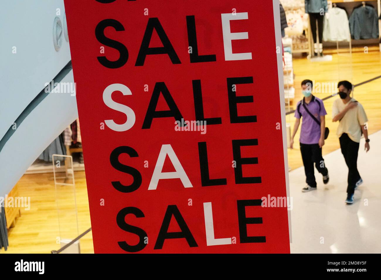 Shoppers are seen behind a sales advertisement at shopping mall in ...