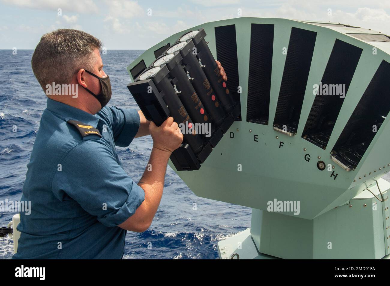 220714-O-QR492-1002-CA  PACIFIC OCEAN (July 14, 2022) Royal Canadian Navy Sailor 1st Class Josh Reves, Naval Electronic Sensor Operation, loads rounds into the Multi Ammunition Softkill System (MASS) on board Royal Canadian Navy frigate (FFH 331) HMCS Vancouver during Rim of the Pacific (RIMPAC) 2022. Twenty-six nations, 38 surface ships, four submarines, nine national land forces, more than 30 unmanned systems, approximately 170 aircraft and more than 25,000 personnel will train and operate in and around the Hawaiian Islands and Southern California, June 29 to Aug. 4. The world’s largest inte Stock Photo