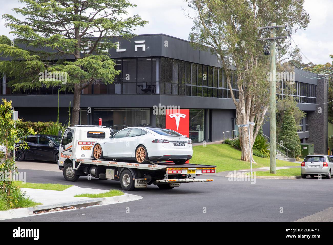 Tesla White Model S, 2015 model, on a tow repair breakdown truck driving past Tesla Showroom in Chatswood,Sydney,NSW,Australia Stock Photo
