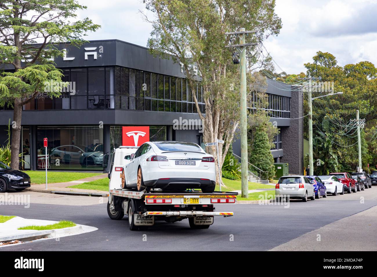Tesla White Model S, 2015 model, on a tow repair breakdown truck driving past Tesla Showroom in Chatswood,Sydney,NSW,Australia Stock Photo